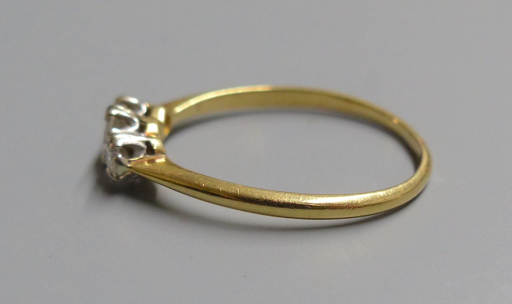 A yellow metal (tests as 18ct) and three stone diamond ring, size O, gross 2.2 grams.